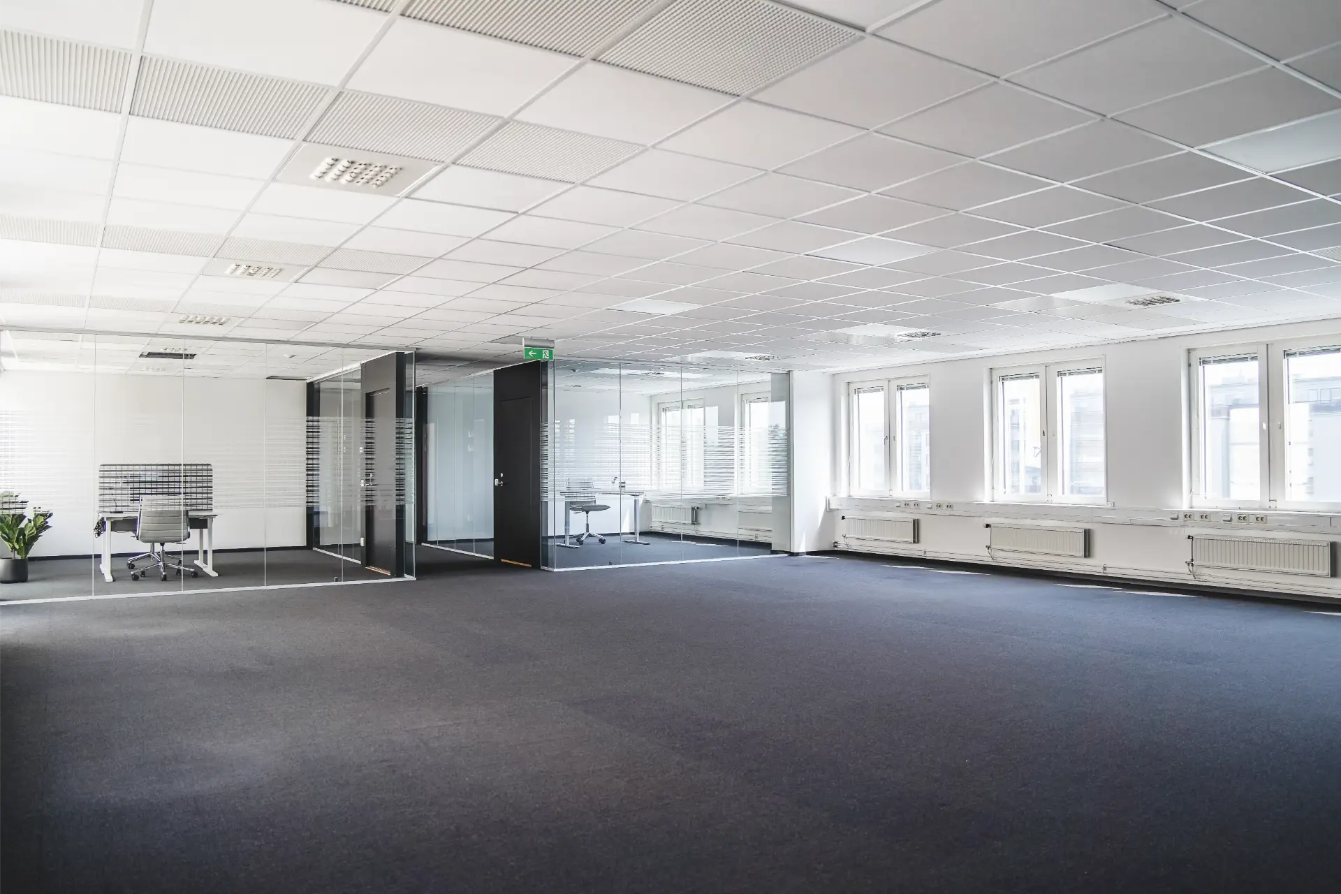 En tom kontorslokal med fönster och en svart matta.